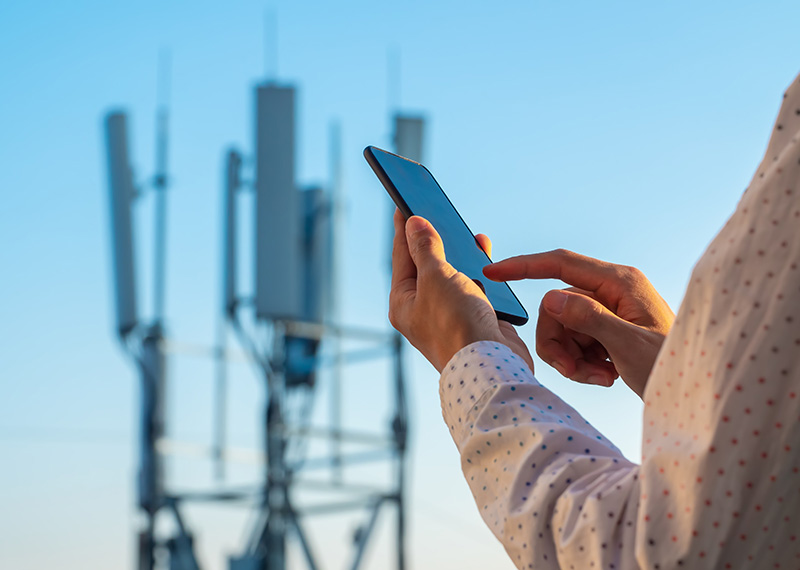 Communications tower with man using mobile phone