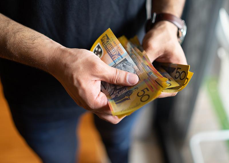 A person holds a bunch of fifty dollar notes in their hands. 