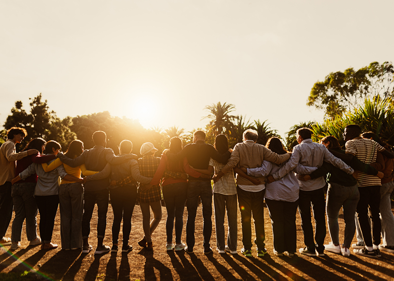 Back view of happy multigenerational people having fun in a public park during sunset time